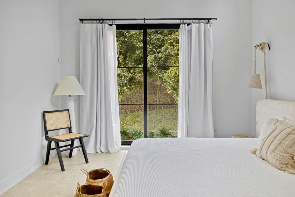 Wake up to serene garden views through floor-to-ceiling windows in your minimalist retreat, where crisp linens and natural light create pure tranquility.