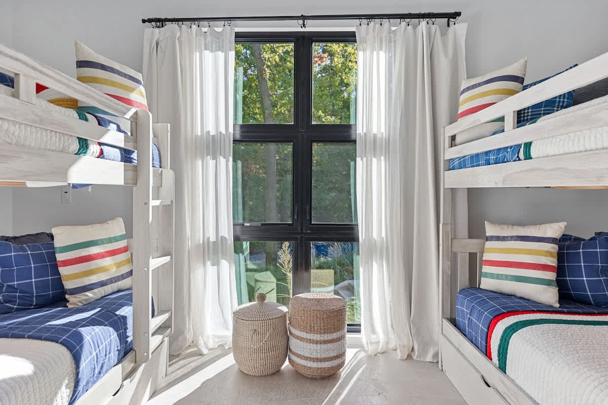 Bright and stylish bunk room with cozy bedding and serene garden views.