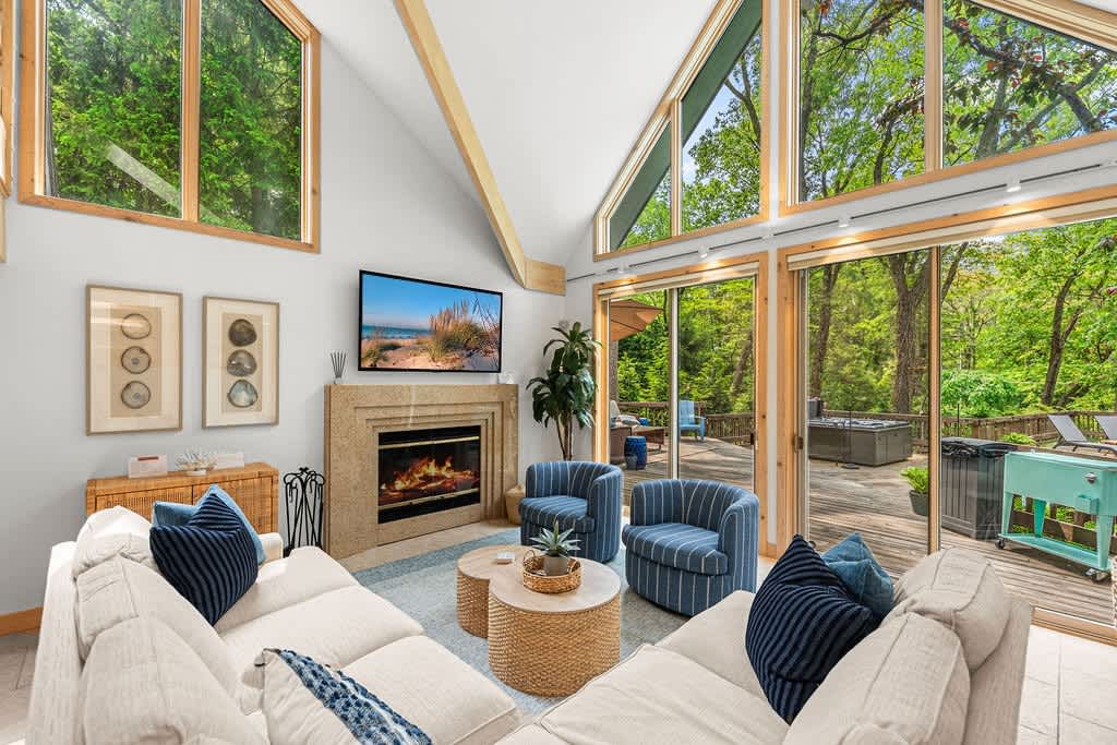 Wall of windows, fireplace glow, and forest all around.