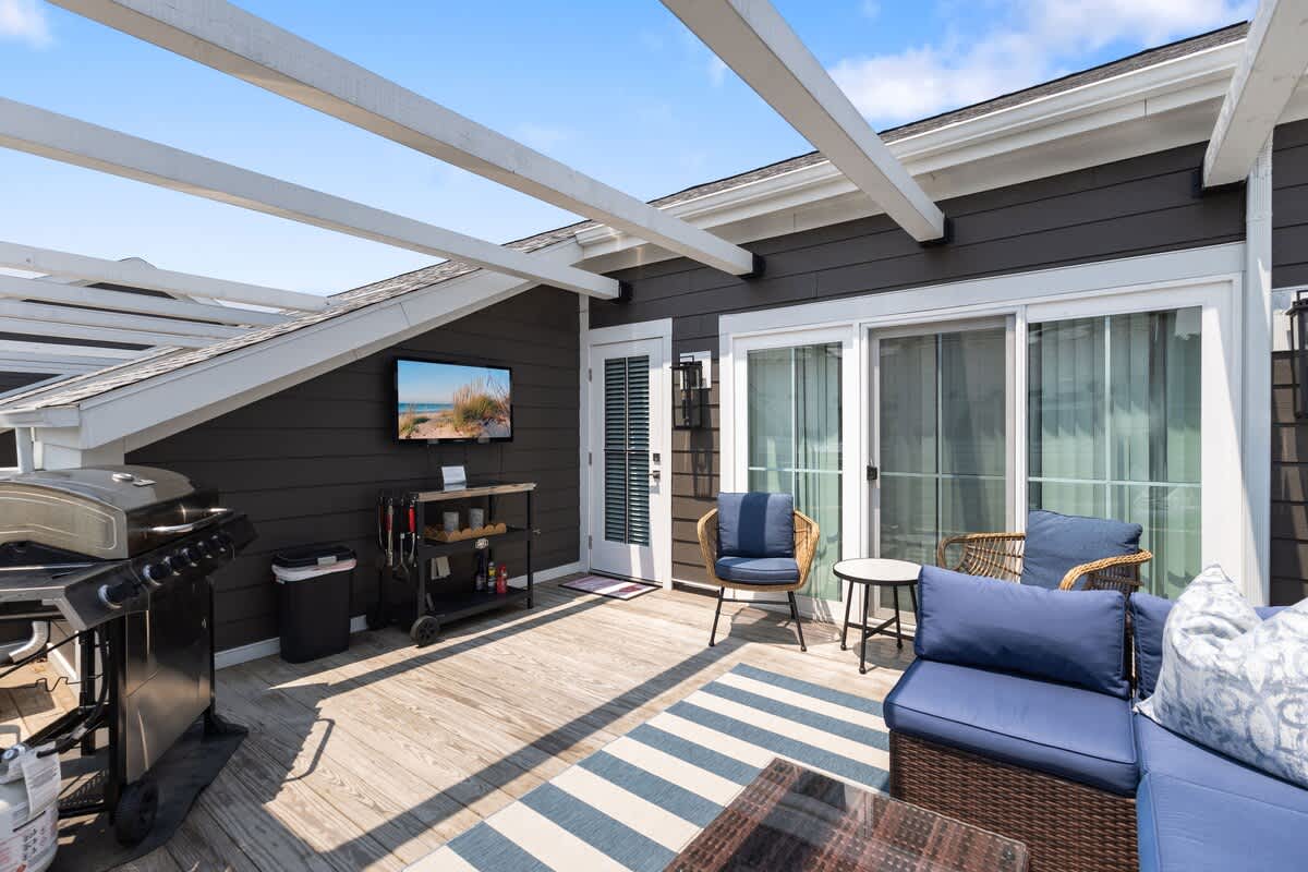 Lounge in style with grill, TV, and sunny rooftop vibes.