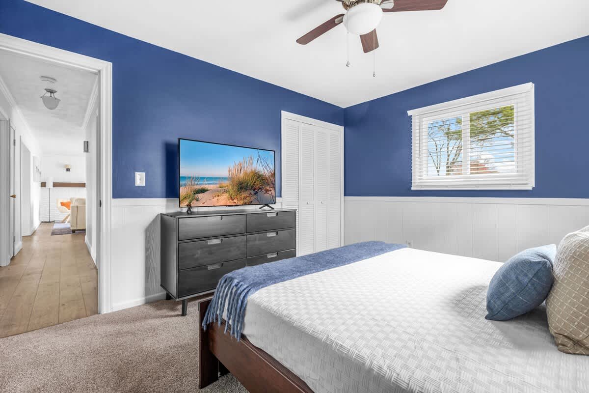 Binge, chill, and snooze in this bold blue bedroom with a smart TV and plush queen bed.