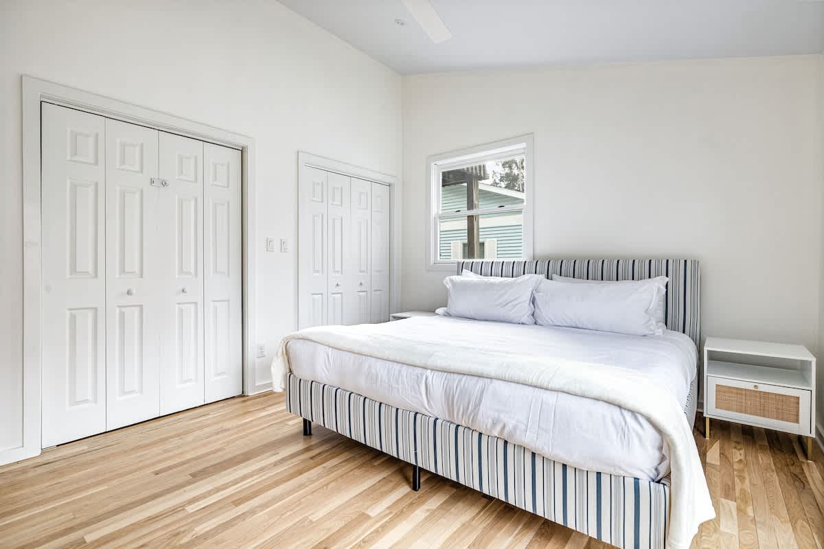 Breezy meets classy in this bright, airy bedroom! Striped charm, fresh linens, and pure comfort await!