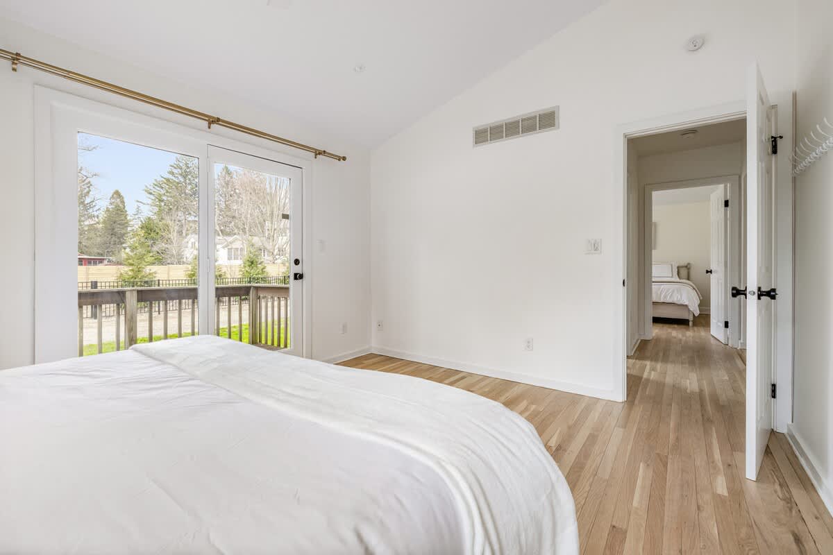 This room feels so bright and calming. The natural light from the sliding doors and the light wood floors give it such an airy, welcoming vibe. That peek into the second bedroom adds a nice sense of flow between the spaces.