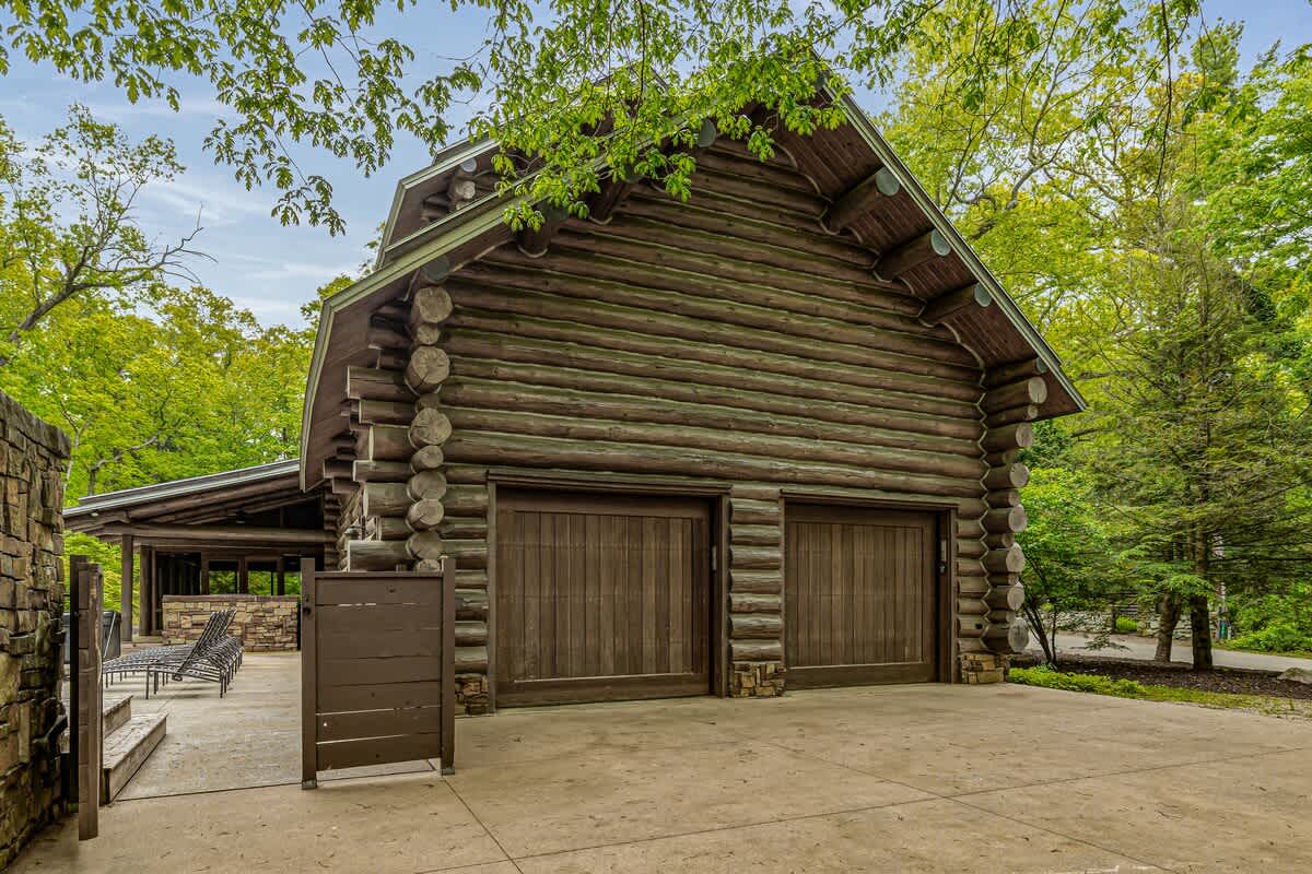 This stunning log home features two spacious garages and a welcoming driveway.