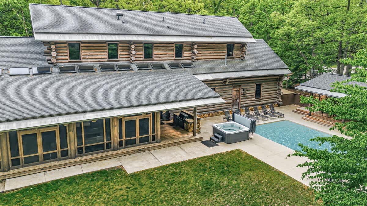 A private log estate with pool, hot tub, and covered lounging in nature.