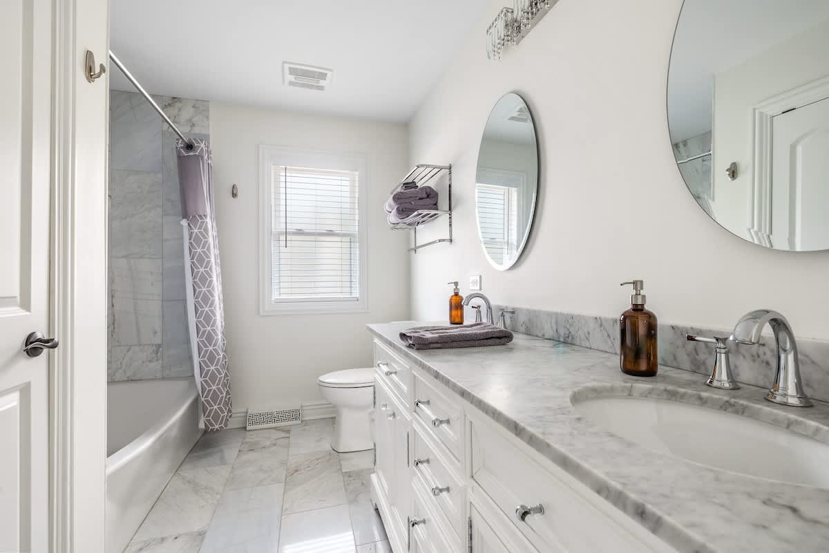 Modern bath with marble, double sinks, tub, and luxe essentials included.