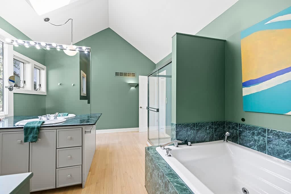 A spacious primary retreat with a soaking tub and calming green tones.