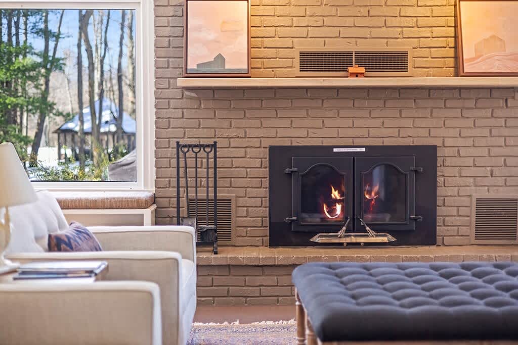 A crackling hearth brings warmth to The Farmhouse’s bright living room.