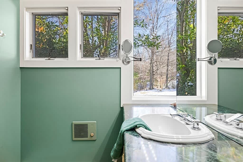 A serene primary bath with refreshing light and views of the property.