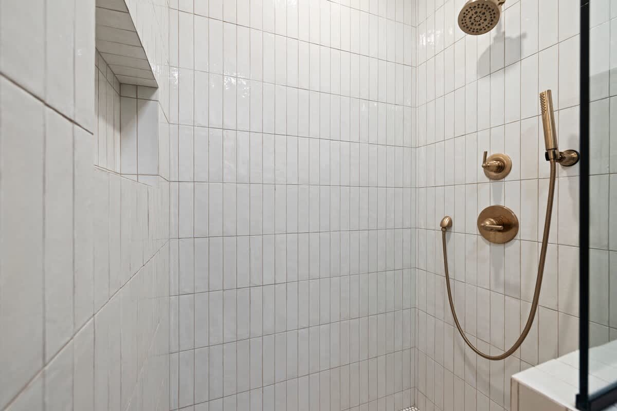 A modern walk-in shower with brass accents and quiet elegance.