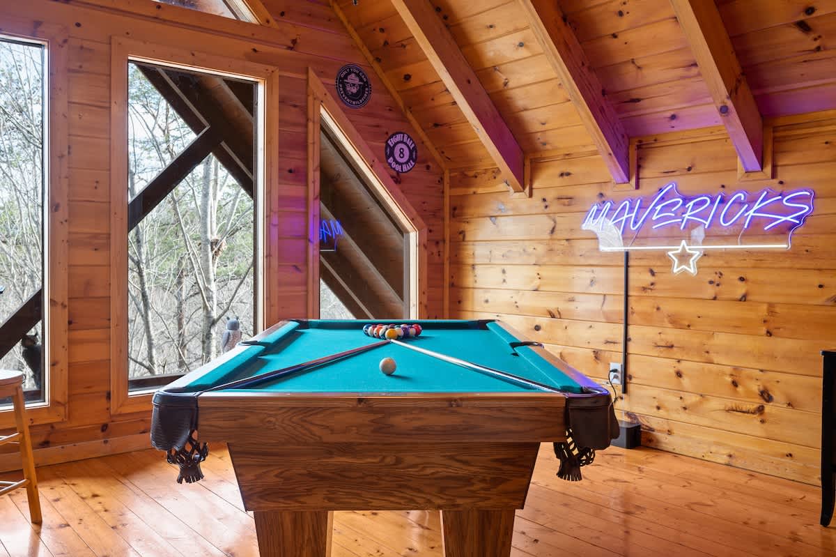 A neon sign lights the game room area, including NFL Blitz!