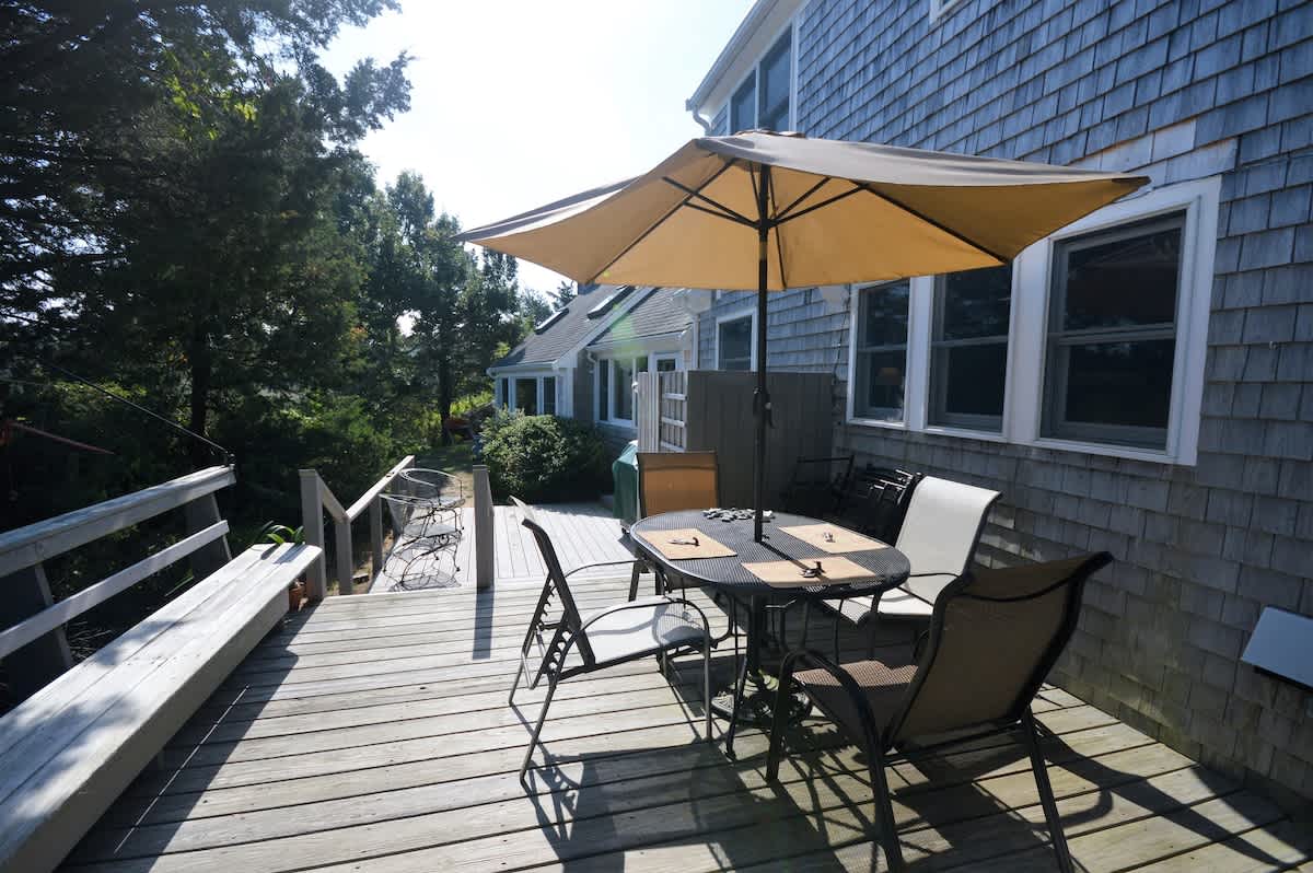 Spacious deck with an outdoor dining table, perfect for summer meals overlooking the peaceful Eastham landscape.