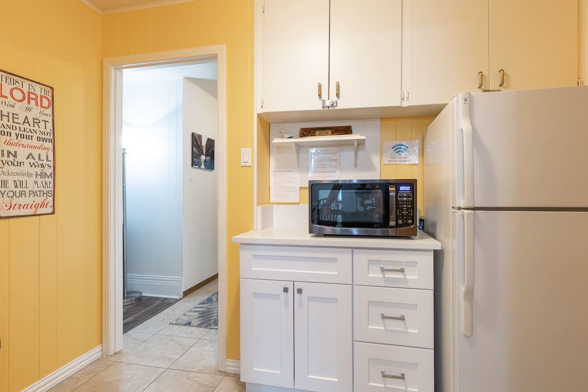 Conveniently store and access food with extra pantry space, including a microwave and additional fridge for quick meals and beverage storage.