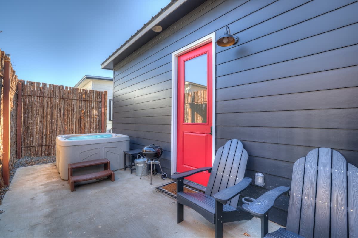 On the rear porch, you'll find a soothing hot tub, a compact charcoal grill (charcoal not included), and two Adirondack chairs for relaxation.