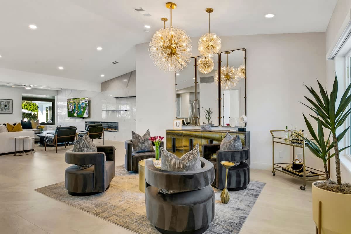 Gather in style in this elegant lounge featuring designer chandeliers, velvet seating, and a luxe bar cart setup.