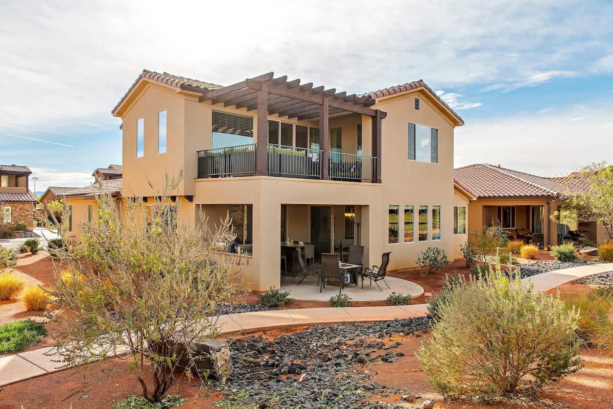Back exterior with balcony and lower patio just steps from pool