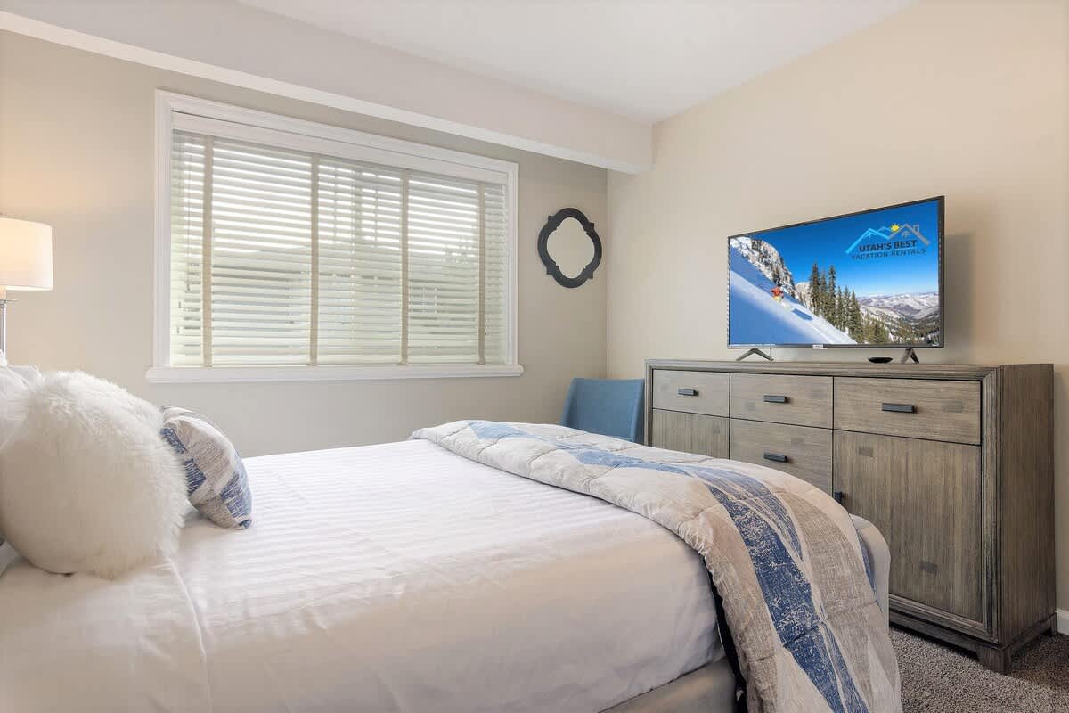 Bedroom 2 with queen bed, dresser, TV and a park view