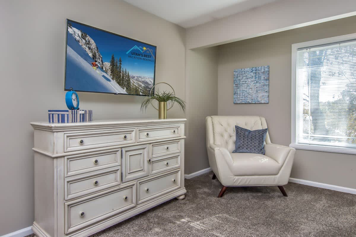 Master suite with chair, dresser and large TV