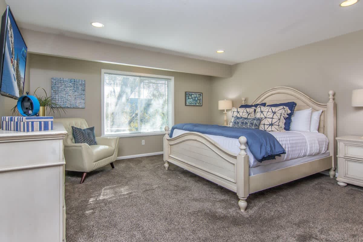 Master suite with king bed, dresser, chair and TV