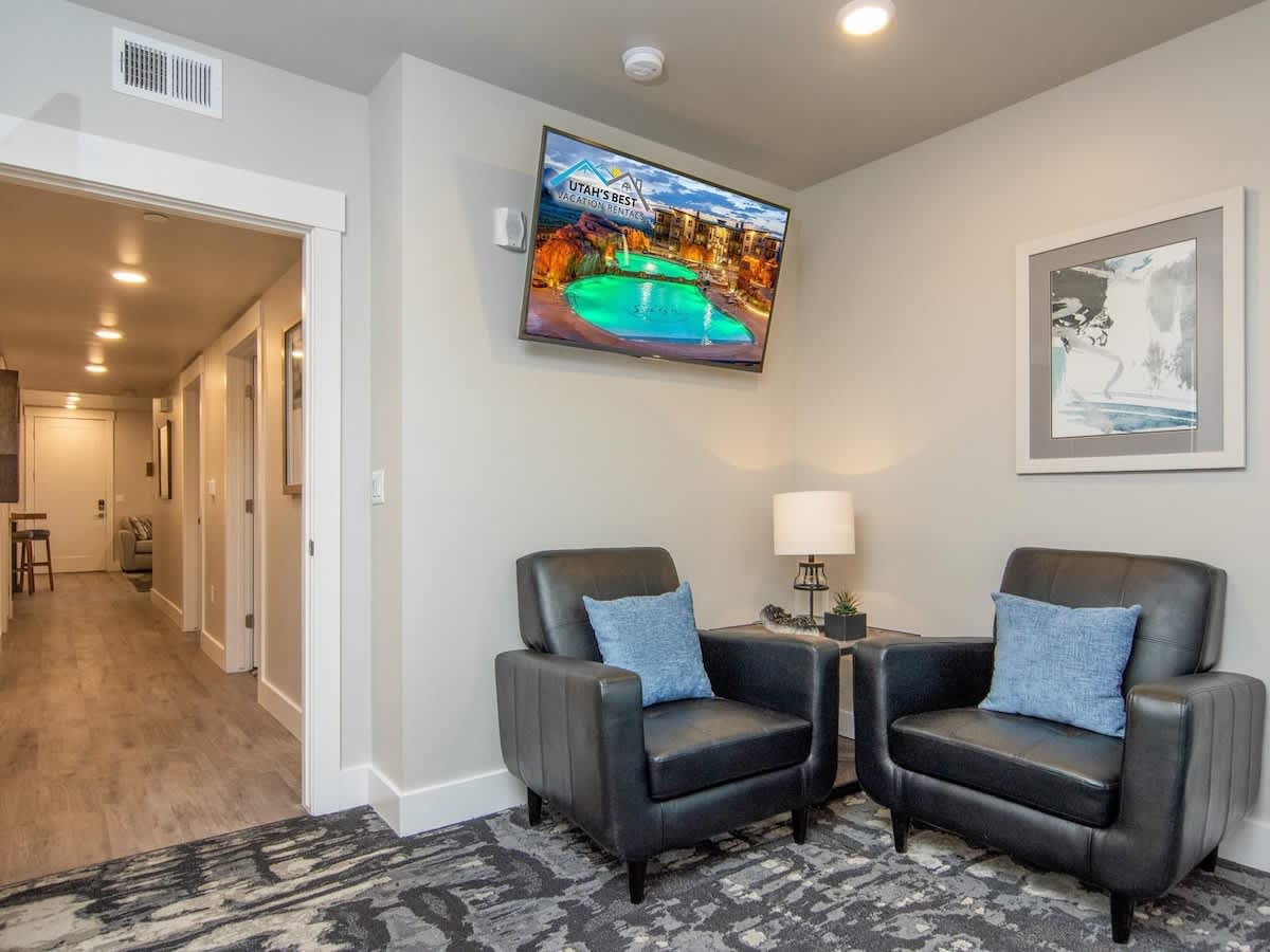 Sitting area in master suite with 2 chairs and large TV