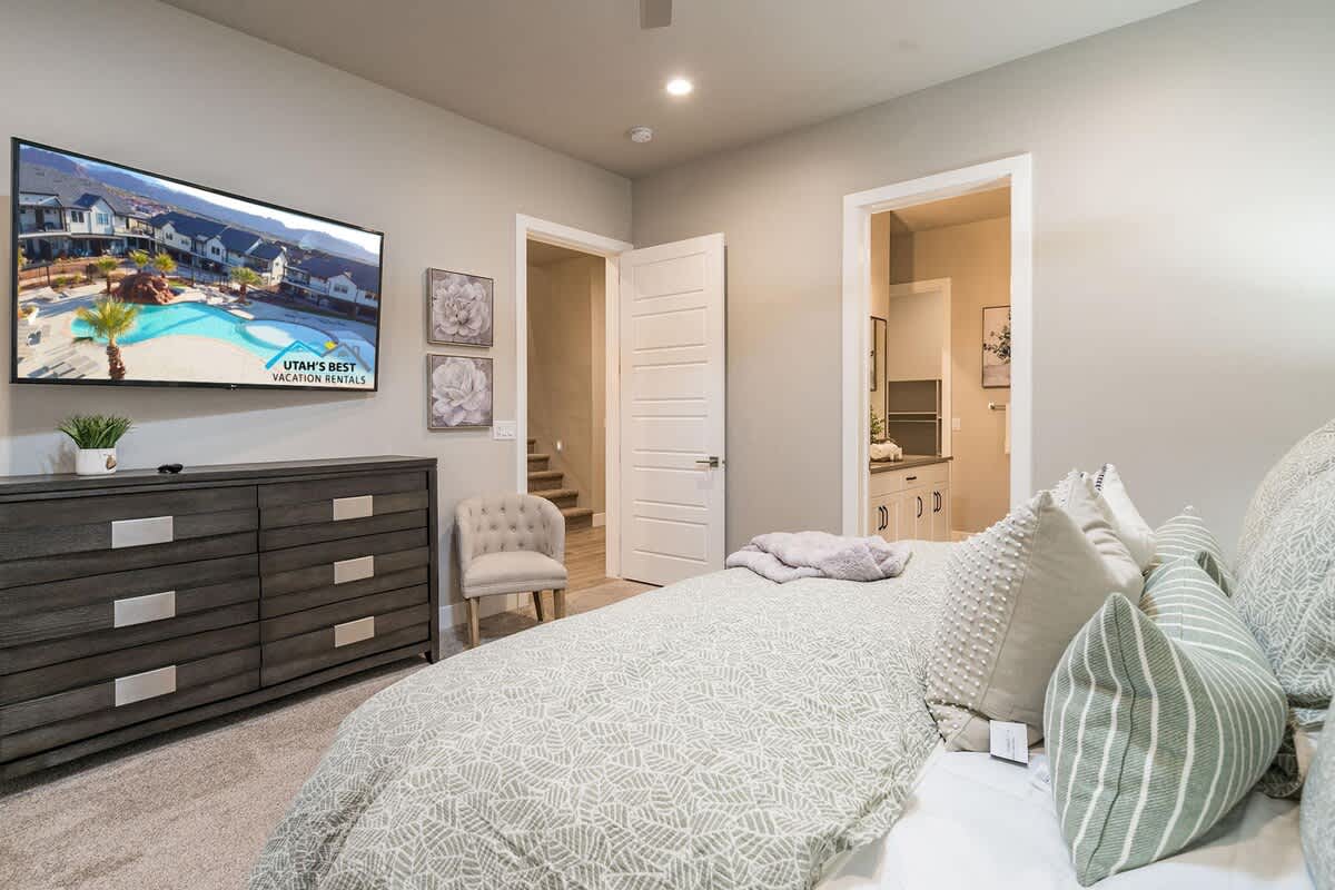 Master bedroom with large TV, dresser, and chair