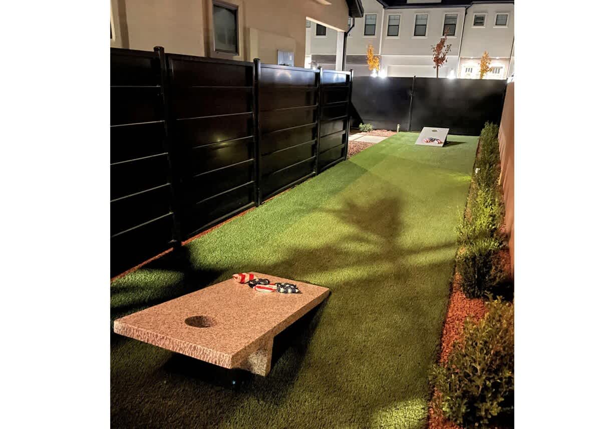 Private custom cornhole court nestled on the side of the home