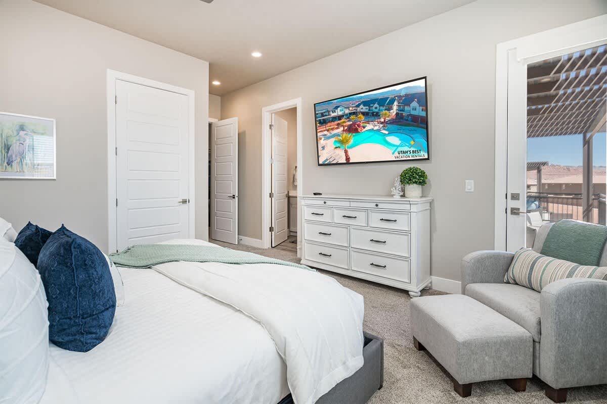 Master bedroom #2 upstairs with TV, chair and balcony with pool 