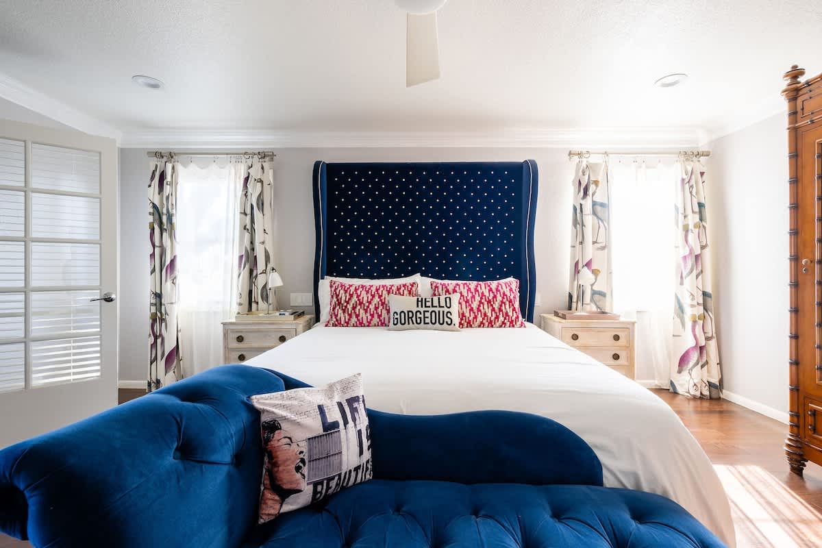 Elegant Master Suite with a plush king bed, luxe velvet chaise, and bright natural light—perfect for a romantic getaway or a restful retreat after wine tasting or golf.