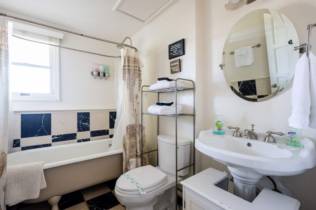 Downstairs full bathroom featuring a combination bathtub and shower, located near the Bricklane Bedroom. Stocked with fresh towels, shampoo, conditioner, and body wash for your comfort.