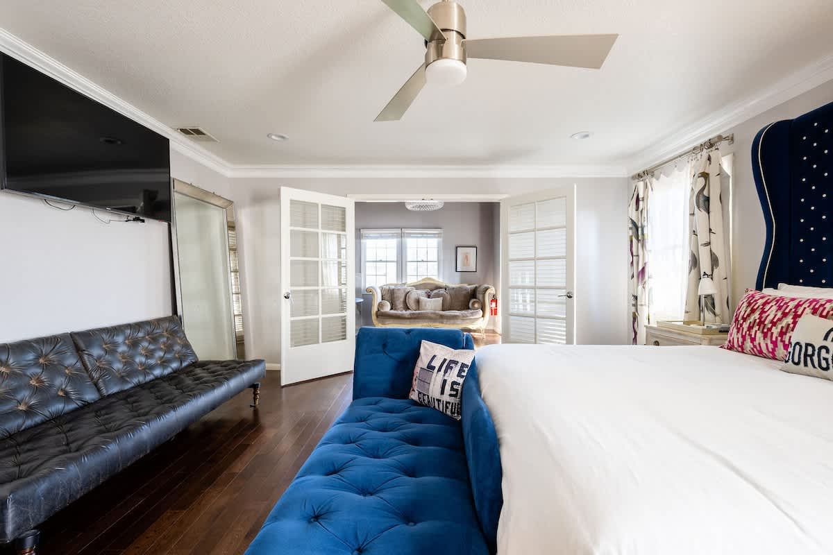 Spacious Master Suite with king bed, chaise lounge, and extra futon for added sleeping space. Bright windows and French doors open to a private retreat—ideal for families, couples, or business travelers seeking comfort and style.