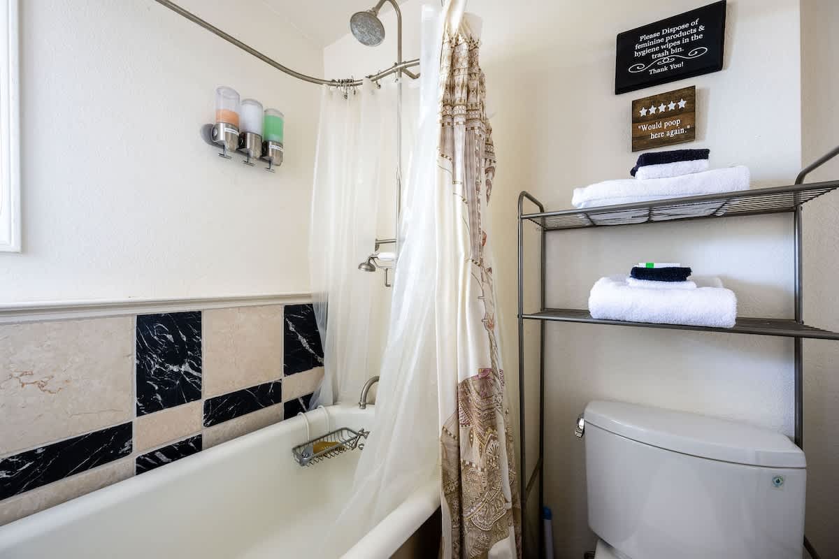 Downstairs full bathroom featuring a combination bathtub and shower, located near the Bricklane Bedroom. Stocked with fresh towels, shampoo, conditioner, and body wash for your comfort.