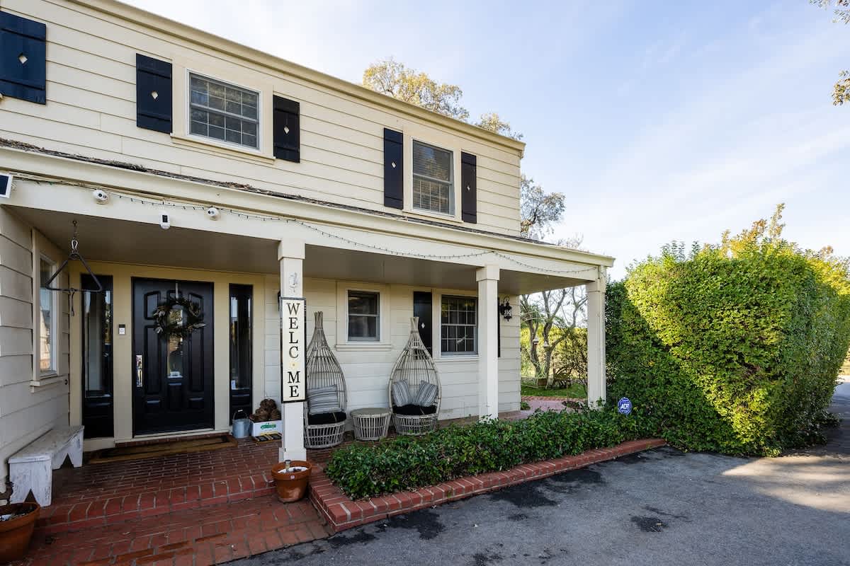 Charming front porch with classic pillars, hanging chairs, and a welcoming entry that sets the tone for your vineyard getaway in San Martin.