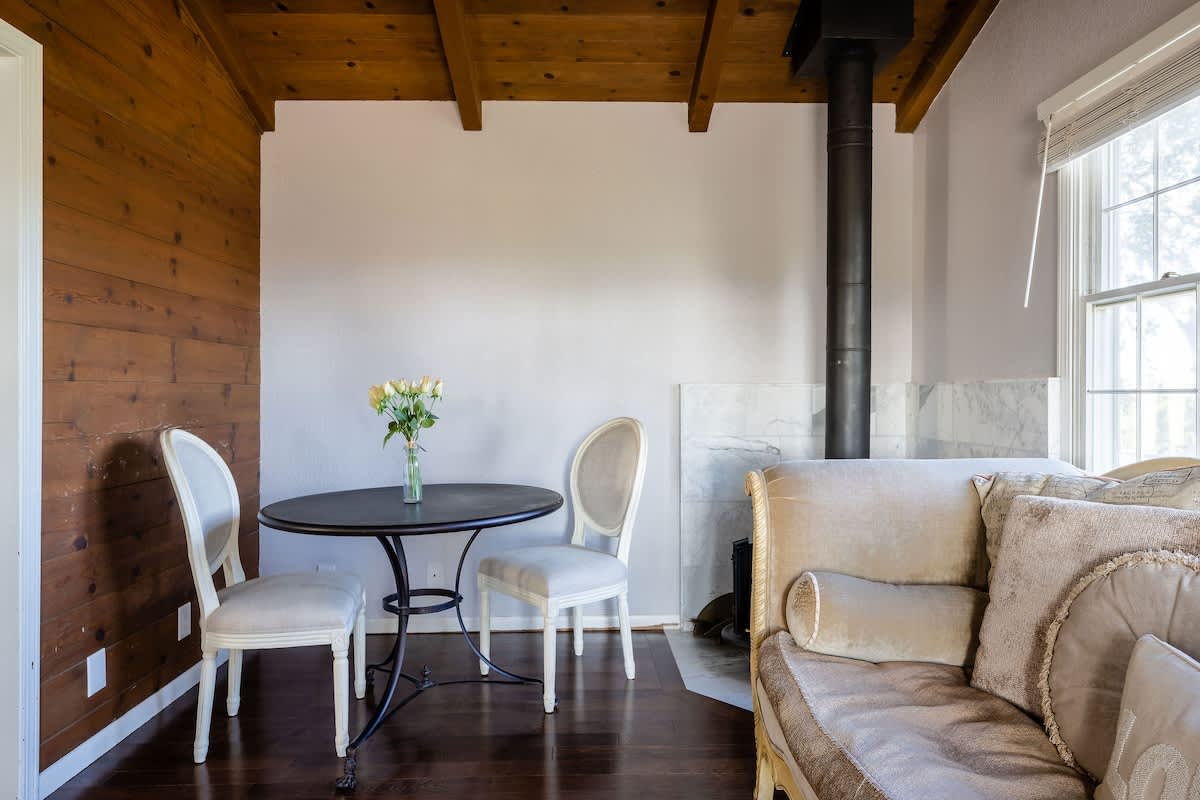 Charming master suite sitting area with intimate bistro table—perfect for morning coffee, wine tasting notes, or a quiet chat by the wood-burning stove.