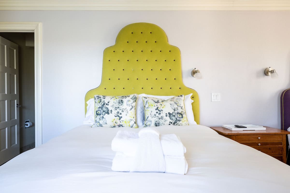 Bright queen bed with plush linens and bold headboard design. Ideal for families needing space, wine lovers on retreat, golfers unwinding, or corporate guests recharging.