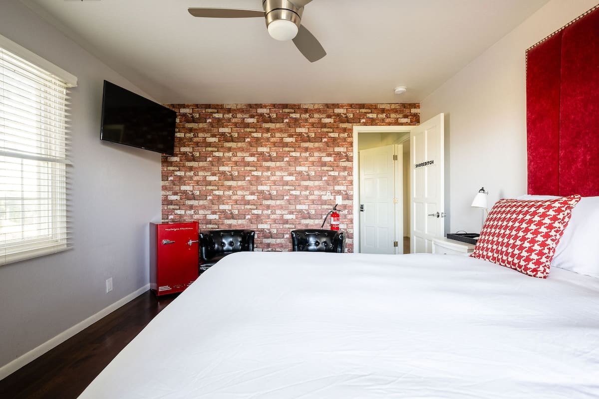 Shoreditch Bedroom blends bold style with comfort—queen bed, brick accent wall, seating nook, and smart TV make it ideal for couples or friends looking for a fun and stylish stay.
