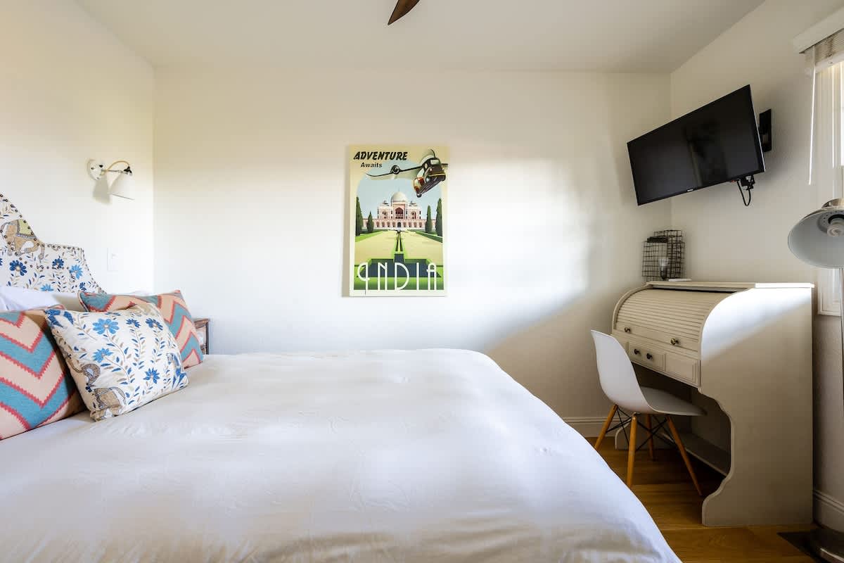 Downstairs Bricklane Bedroom with queen bed, smart TV, and desk space. Ideal for families, wine country explorers, golf getaways, or corporate guests visiting San Martin and nearby Silicon Valley.