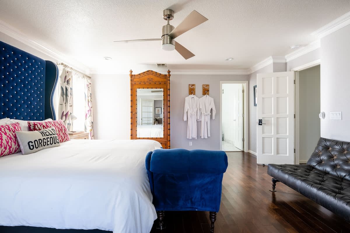 Spacious master suite with king bed, luxe velvet chaise, full-length mirror, and plush robes—perfect for unwinding in comfort after wine tasting, golf, or a busy workday.
