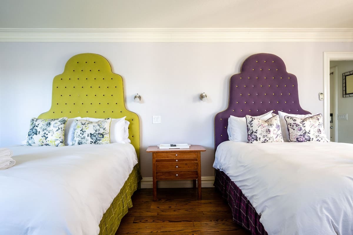 Colorful and cozy, this first-floor room features two plush queen beds with vibrant headboards—perfect for families or friends who want comfort and style during their stay.