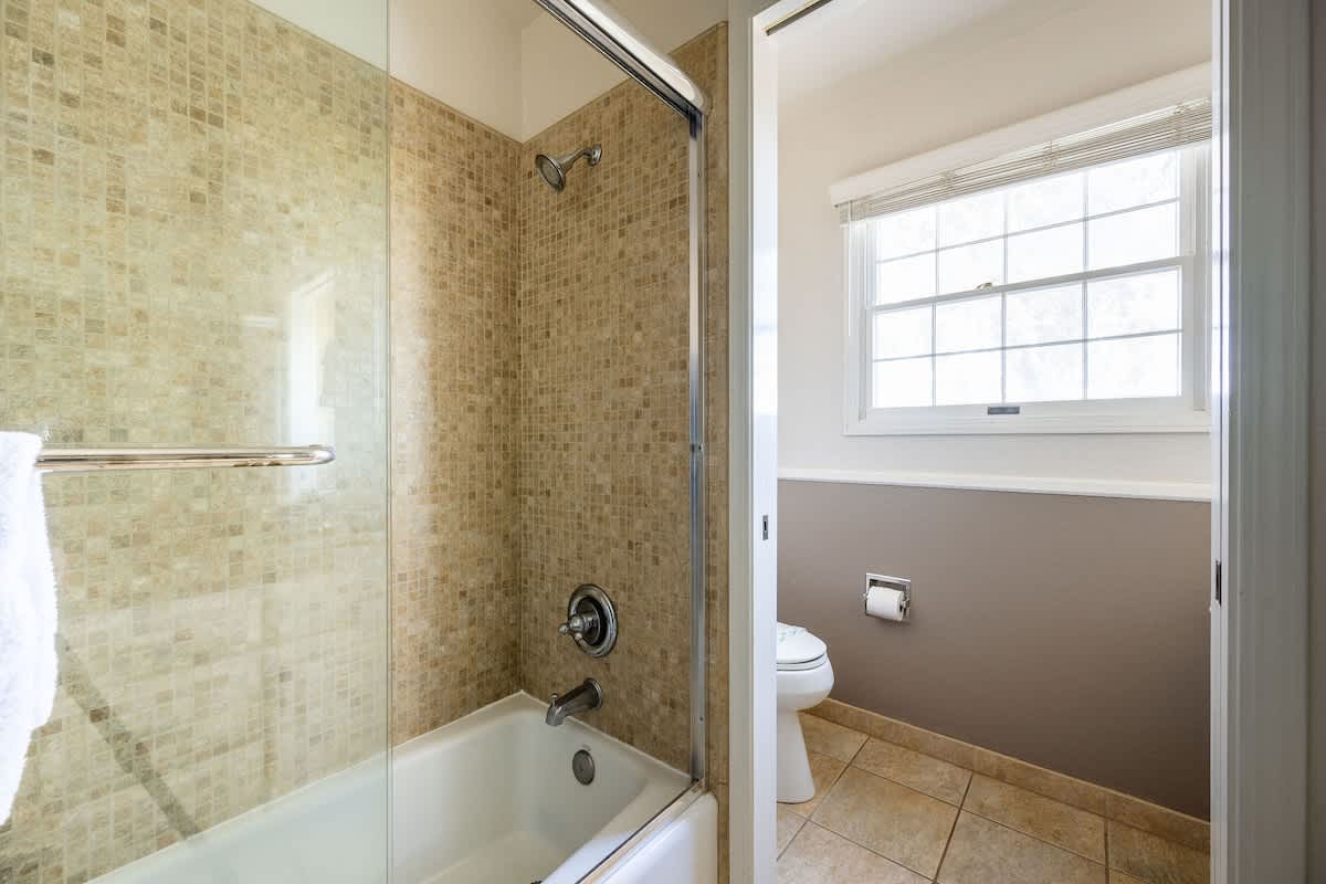Modern tiled tub/shower combo with glass enclosure, offering both comfort and convenience for guests in the Shoreditch Bedroom