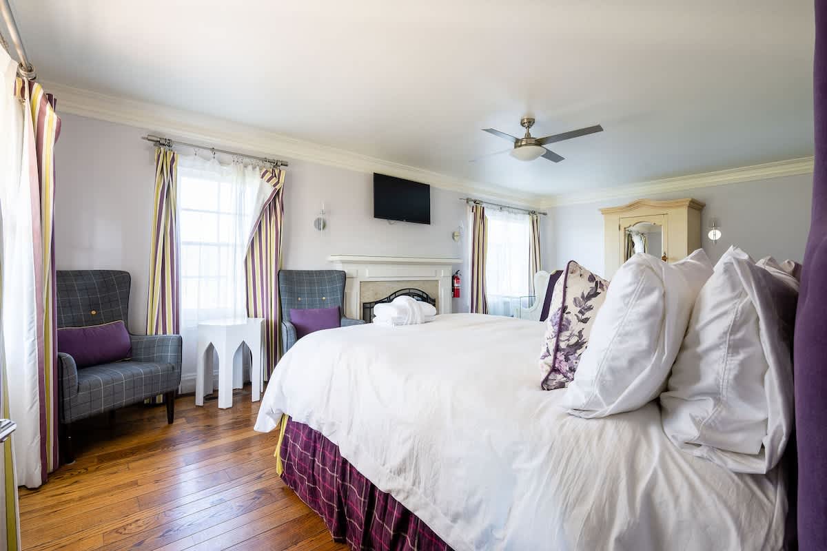 Elegant first-floor bedroom with two queen beds, cozy seating, and a fireplace view—perfect for families, wine country weekends, golf trips, or corporate retreats.