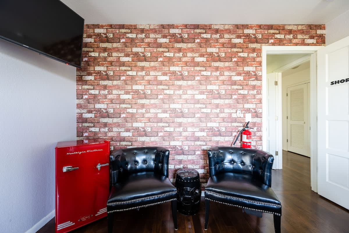 The Shoreditch Bedroom includes its own private lounge with leather chairs, mini fridge, and bold London-style design—ideal for golfers to relax after a day on the championship courses nearby.