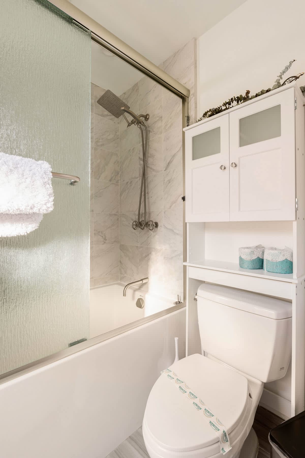 Modern full bath with marble tile, glass shower door, and soaking tub for ultimate comfort