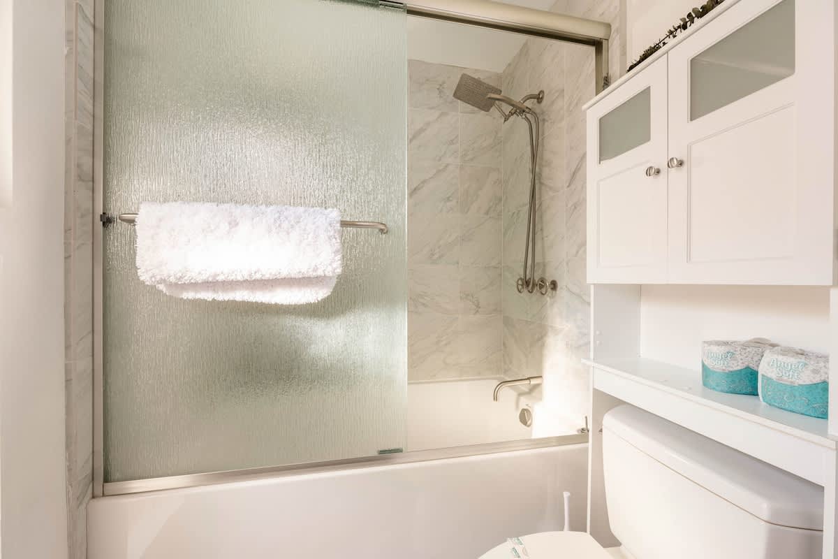 Relax in a spa-like bathroom with a deep soaking tub, rainfall shower, sleek vessel sink, and marble counters. Modern finishes and fresh towels create a pampering retreat after a day at the beach.