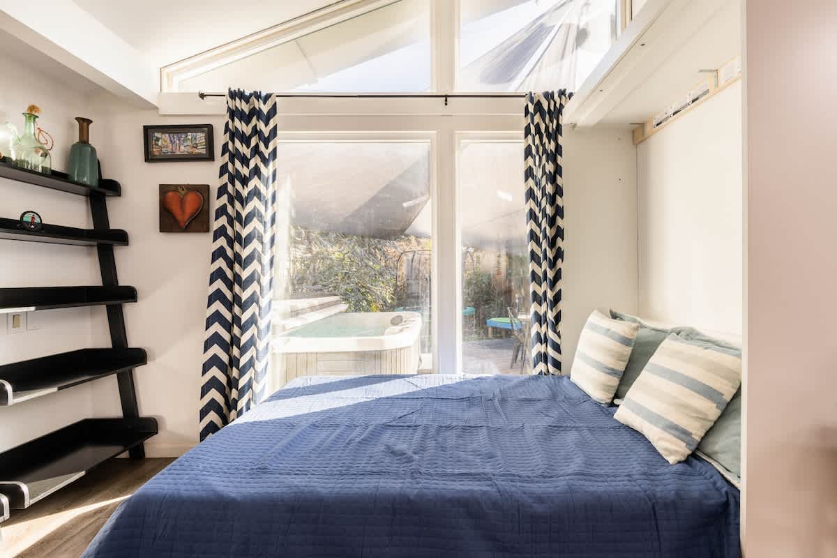 Spacious Murphy bed in the living room with garden + hot tub views—great for families, extra guests, or business travelers needing flexibility.