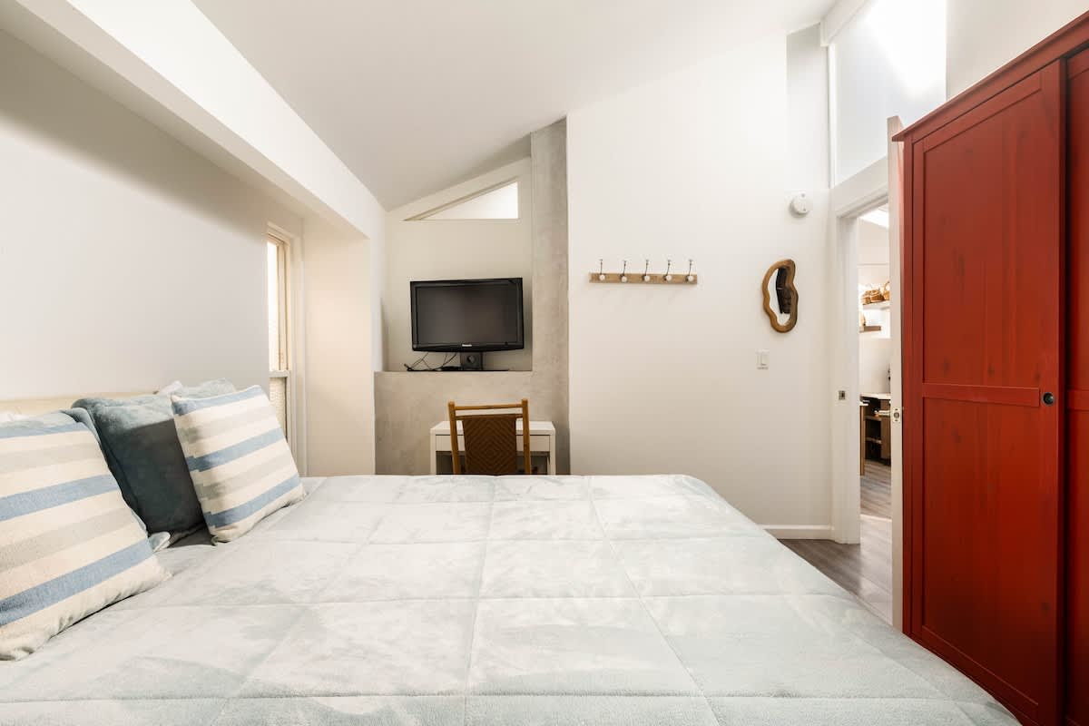 Bright bedroom with queen bed, TV, and workspace. Perfect for couples unwinding, families needing extra comfort, or business travelers who want a cozy spot to recharge after a productive day.