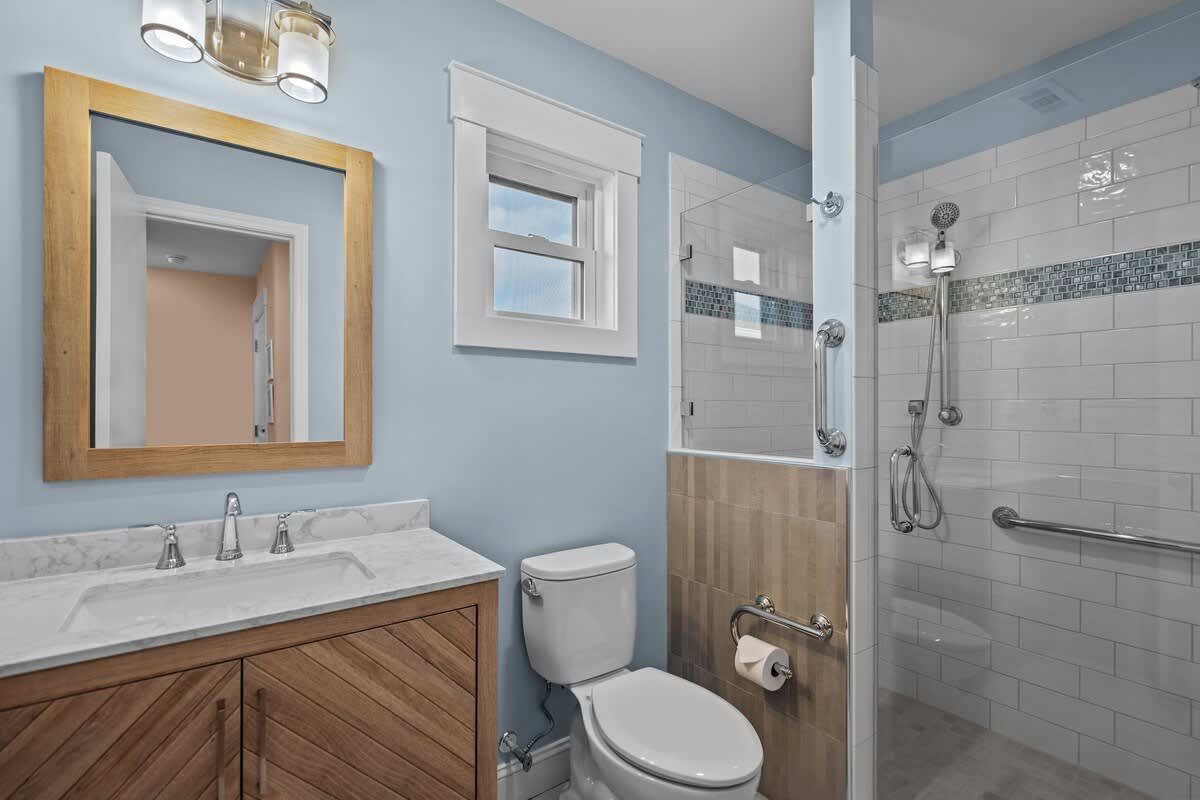 Brand new bathroom build in 2023 features an easy step in shower bench, safety grab bars and two shower heads. The toilet paper holder doubles as a fixed grab bar as well. 