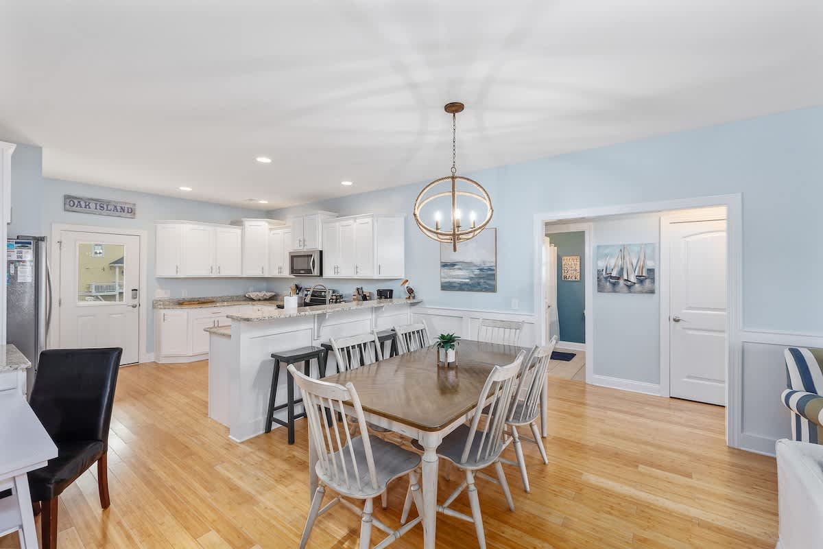 The dining table seats six comfortably, with additional seating available at the kitchen bar.