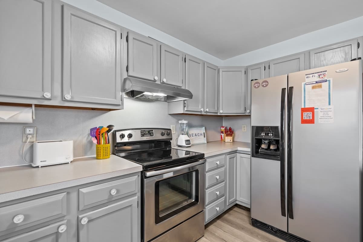 The kitchen features stainless steel appliances, a side-by-side fridge, flat top stove and plenty of counter space.