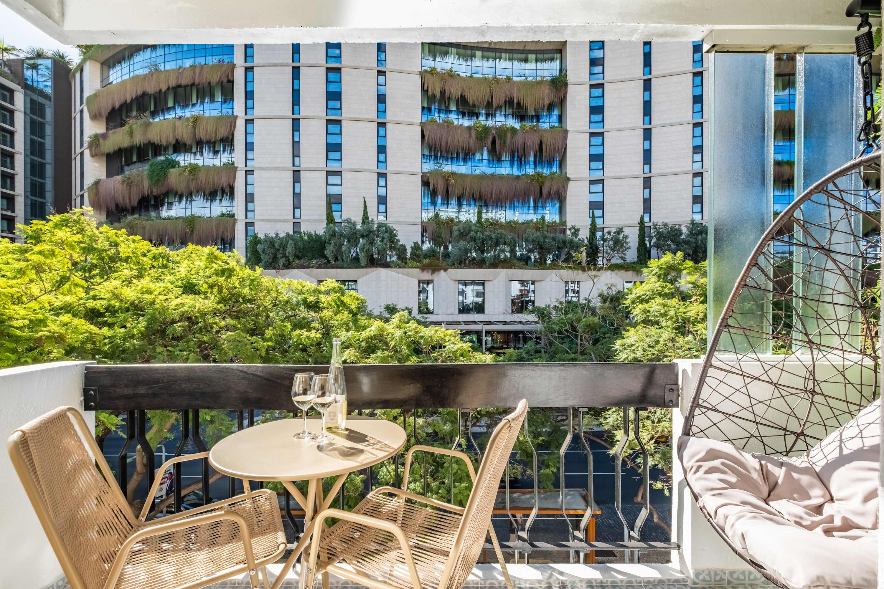 Balcony table and hanging chair facing the green facade opposite