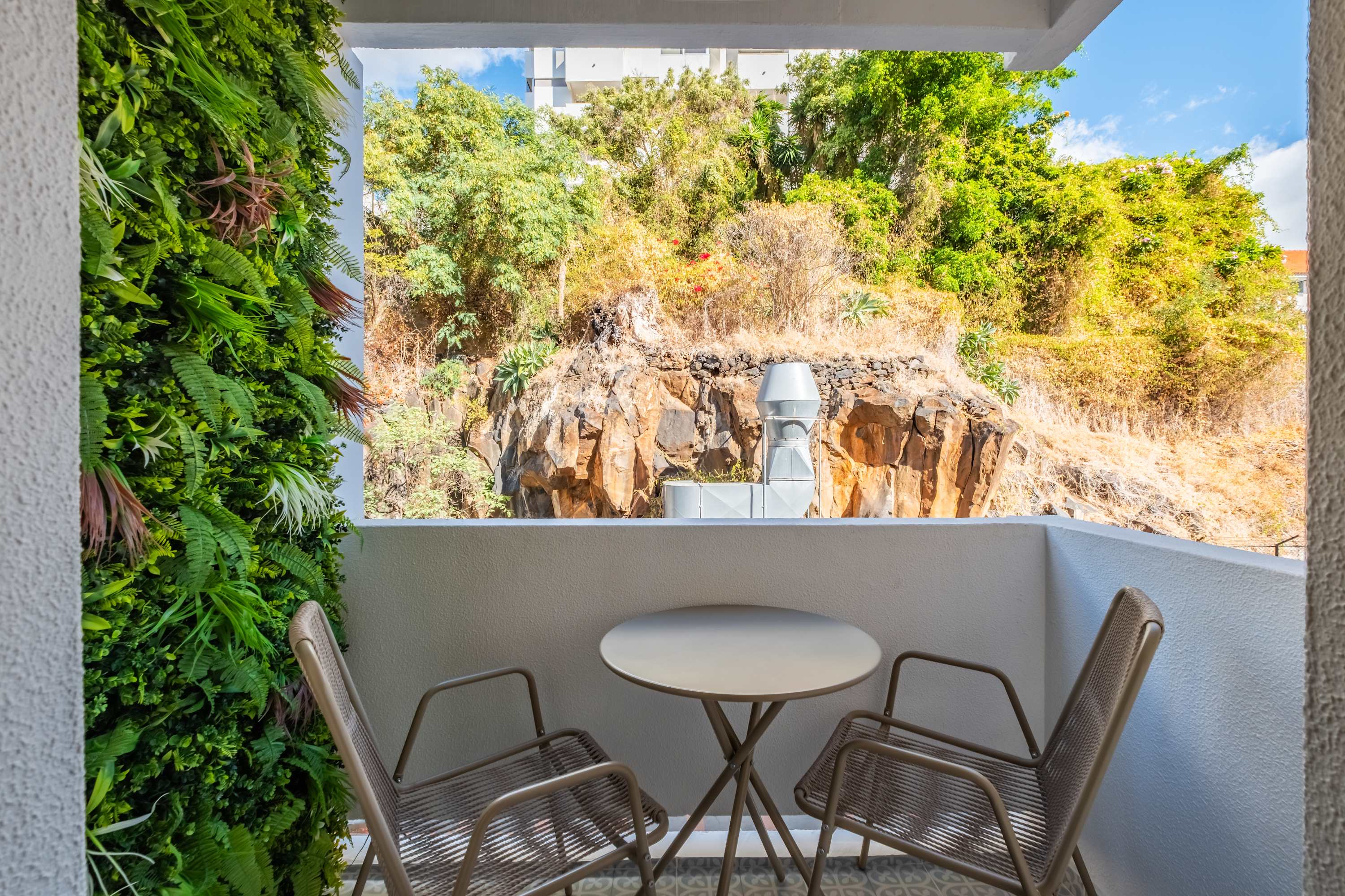 Private balcony with bistro table and planted cliff behind